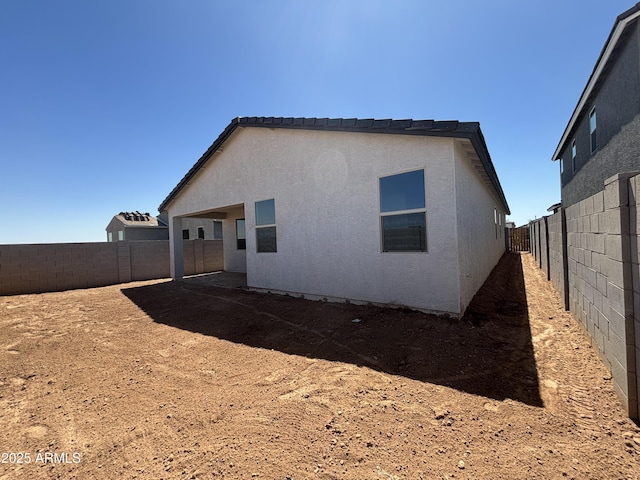 rear view of property featuring a fenced backyard and stucco siding