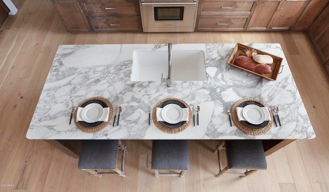 interior space with sink, light stone countertops, stove, and light wood-type flooring