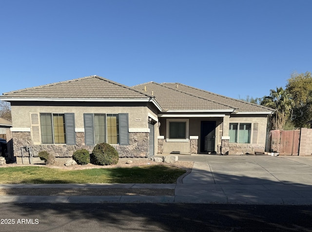 view of front facade with stone siding, a tile roof, and stucco siding