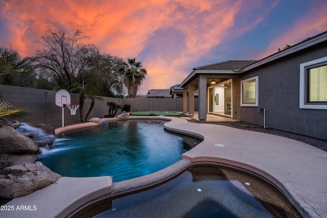 pool at dusk featuring a fenced backyard, a fenced in pool, and a patio