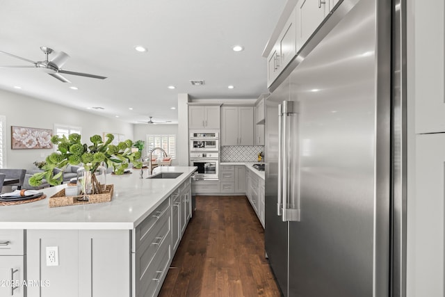 kitchen with visible vents, decorative backsplash, appliances with stainless steel finishes, gray cabinetry, and a sink