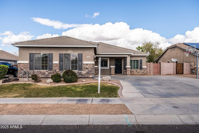 view of front of property featuring stone siding, fence, and stucco siding