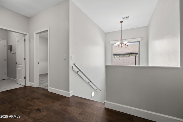 interior space with baseboards, visible vents, wood finished floors, an upstairs landing, and a chandelier