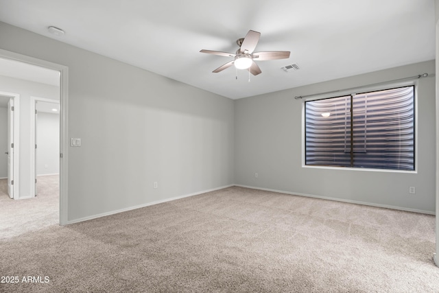 empty room with ceiling fan, carpet flooring, visible vents, and baseboards