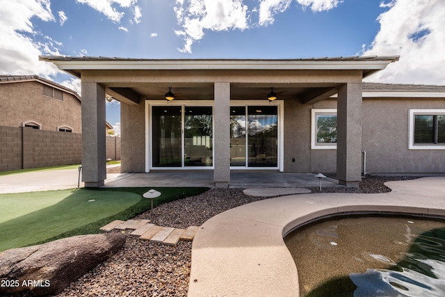 rear view of property featuring stucco siding, ceiling fan, fence, and a patio