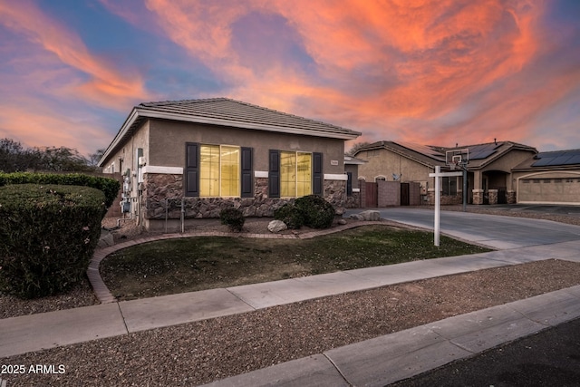 view of front of property featuring driveway, stone siding, a gate, and stucco siding