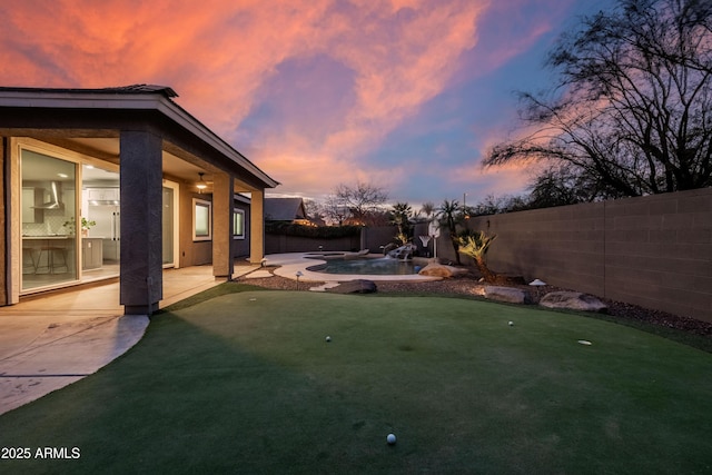 yard at dusk featuring a fenced backyard and a patio