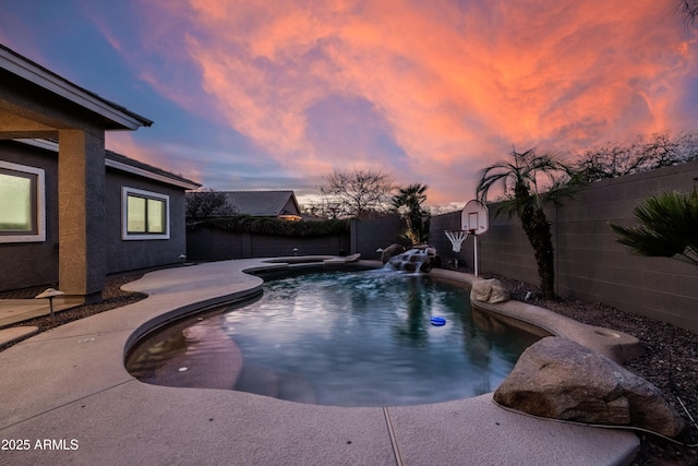 pool at dusk with a fenced backyard