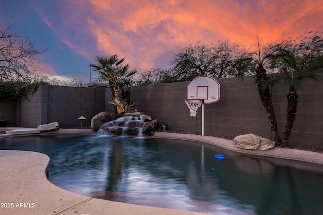 pool at dusk featuring fence