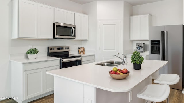 18362 W Hackamore Dr, Wittmann, AZ 85361 - kitchen with stainless steel appliances, white cabinetry, an island with sink, wood finished floors, and a breakfast bar