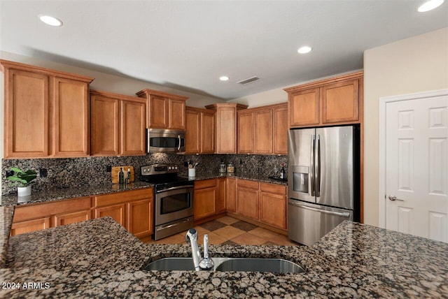 kitchen featuring dark stone countertops, sink, light tile patterned flooring, and stainless steel appliances