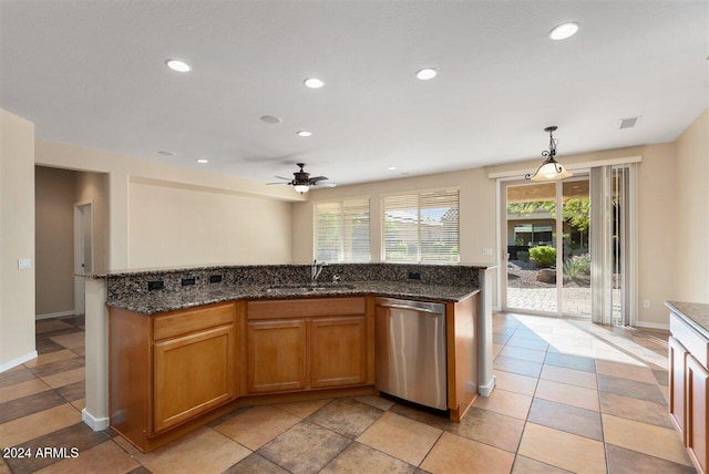 kitchen featuring pendant lighting, a kitchen island with sink, dark stone counters, sink, and stainless steel dishwasher