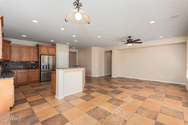 kitchen featuring backsplash, stone counters, hanging light fixtures, ceiling fan, and stainless steel fridge with ice dispenser