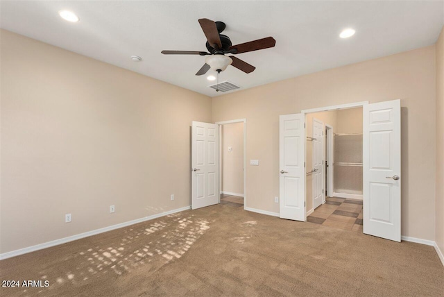 unfurnished bedroom featuring light colored carpet, a spacious closet, and ceiling fan