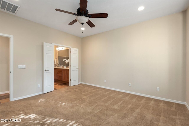 unfurnished bedroom featuring light colored carpet, ceiling fan, and ensuite bathroom