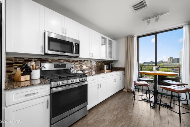 17 W Vernon Ave Unit 412, Phoenix, AZ 85003 - kitchen with visible vents, glass insert cabinets, tasteful backsplash, dark stone countertops, and appliances with stainless steel finishes
