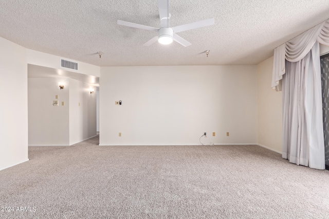 empty room featuring ceiling fan, light colored carpet, and a textured ceiling