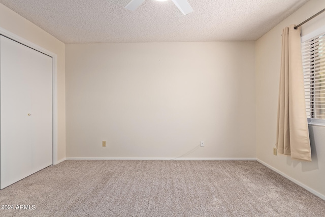 unfurnished bedroom with ceiling fan, a textured ceiling, a closet, and carpet flooring