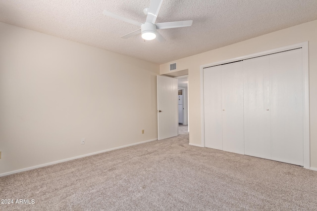 unfurnished bedroom with a closet, light colored carpet, a textured ceiling, and ceiling fan