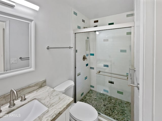 bathroom with vanity, toilet, and a shower with door