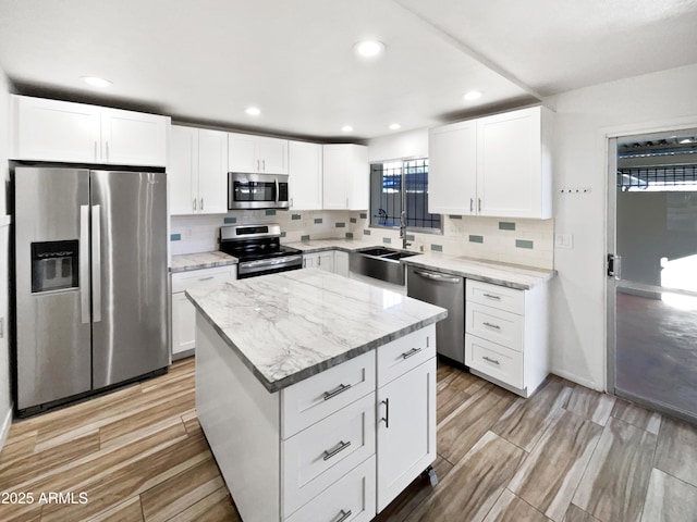 kitchen featuring white cabinets, a kitchen island, sink, and appliances with stainless steel finishes