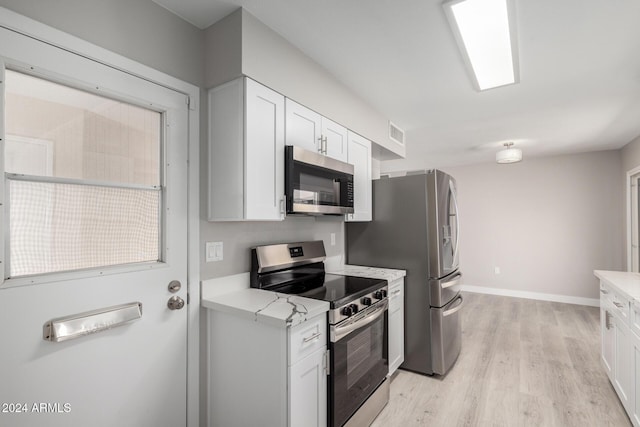 kitchen with white cabinets, stainless steel appliances, and light wood-type flooring