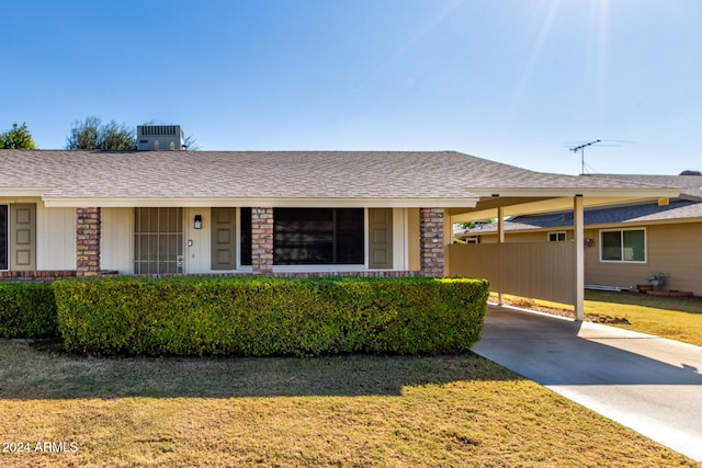 ranch-style home with a carport, cooling unit, and a front yard