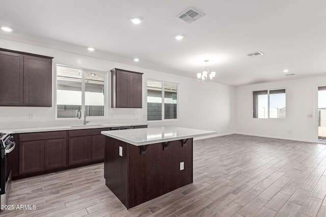 kitchen featuring hanging light fixtures, a kitchen breakfast bar, a kitchen island, sink, and an inviting chandelier