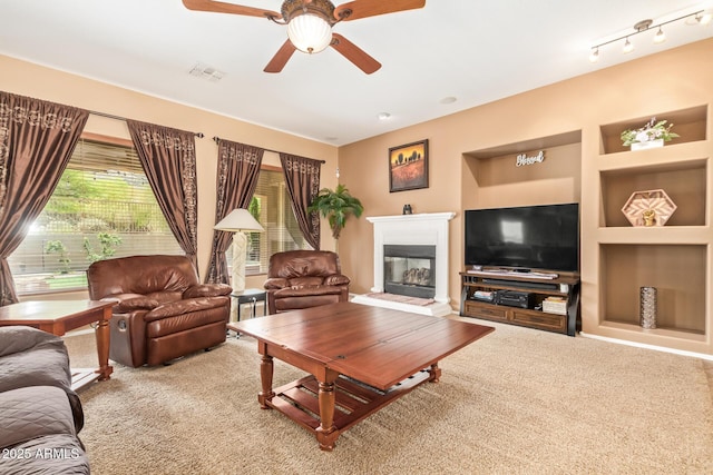 2413 W Kachina Trl, Phoenix, AZ 85041 - living room with carpet flooring, a ceiling fan, built in features, and a glass covered fireplace