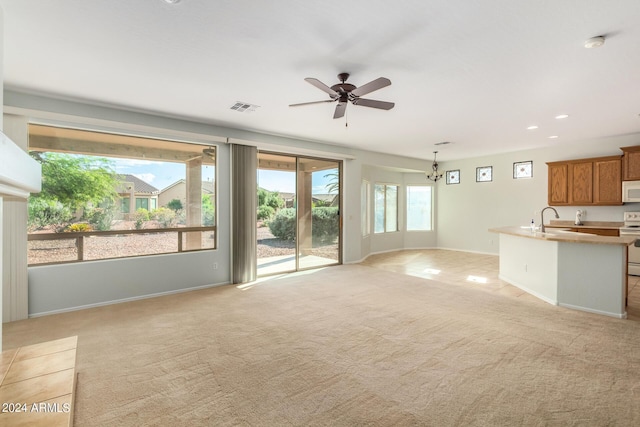 unfurnished living room featuring sink, light colored carpet, and ceiling fan