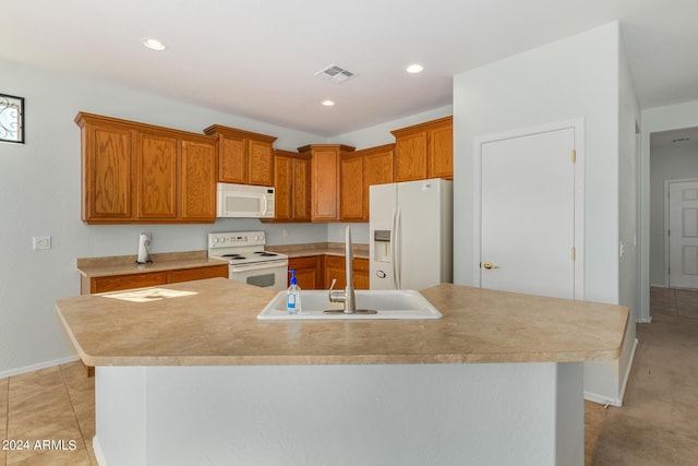 kitchen featuring light tile patterned flooring, white appliances, sink, and an island with sink