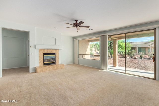 unfurnished living room featuring a tile fireplace, light carpet, and ceiling fan