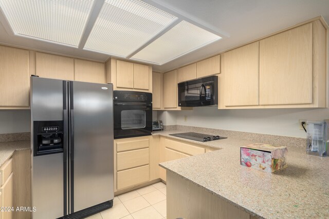 kitchen with light tile floors, light brown cabinetry, and black appliances