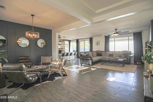 living room with ceiling fan with notable chandelier and hardwood / wood-style floors