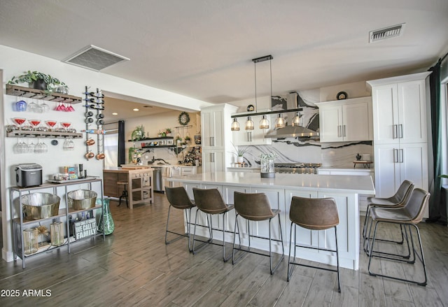 kitchen featuring pendant lighting, a spacious island, a kitchen breakfast bar, and white cabinets