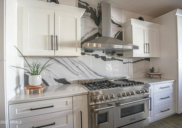 kitchen with dark hardwood / wood-style floors, tasteful backsplash, white cabinets, range with two ovens, and wall chimney range hood