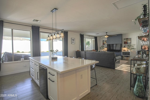 kitchen with pendant lighting, a center island, wine cooler, and white cabinets