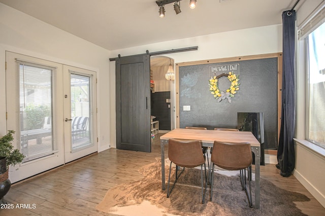 dining space with hardwood / wood-style flooring, a barn door, and french doors