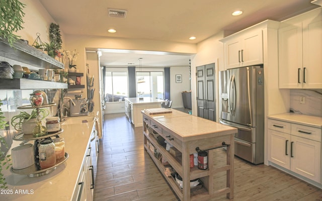 kitchen featuring white cabinetry, stainless steel fridge, dark wood-type flooring, and pendant lighting