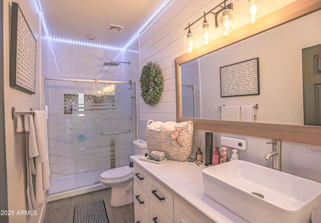 bathroom with wood walls, hardwood / wood-style flooring, vanity, an enclosed shower, and toilet