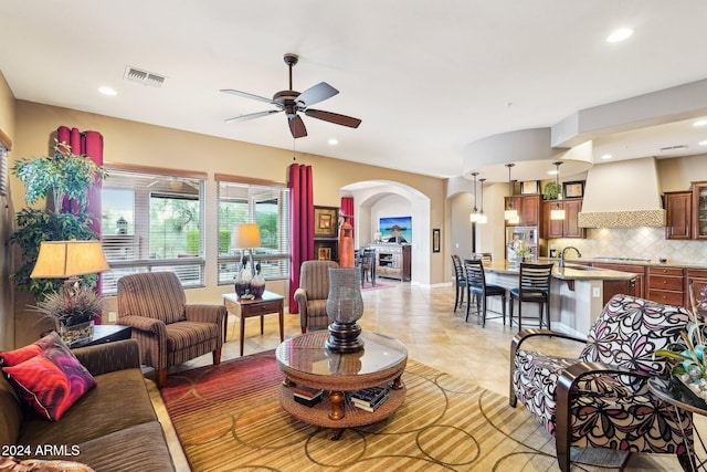 tiled living room featuring ceiling fan and sink