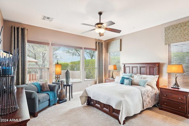 bedroom featuring multiple windows, light colored carpet, and ceiling fan