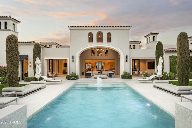 back house at dusk featuring pool water feature, an outdoor living space, and a patio area