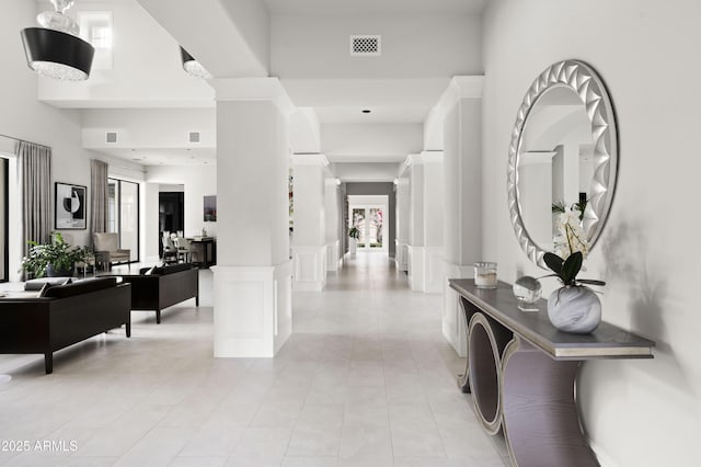 corridor with decorative columns, a high ceiling, and light tile patterned floors