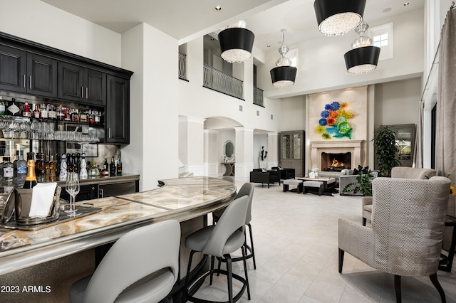 kitchen featuring decorative columns, hanging light fixtures, a towering ceiling, and light tile patterned floors