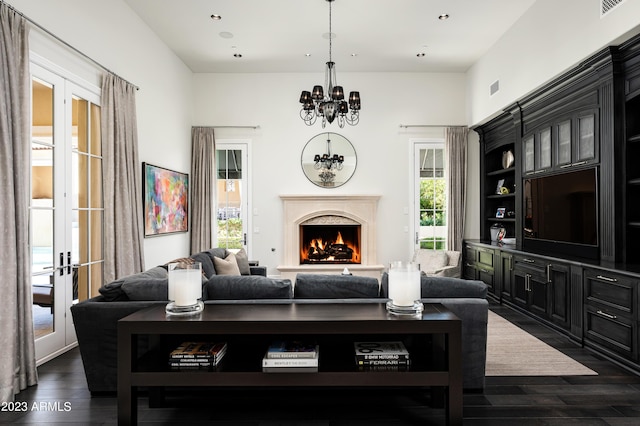 living room featuring dark wood-type flooring, a notable chandelier, a high end fireplace, and french doors