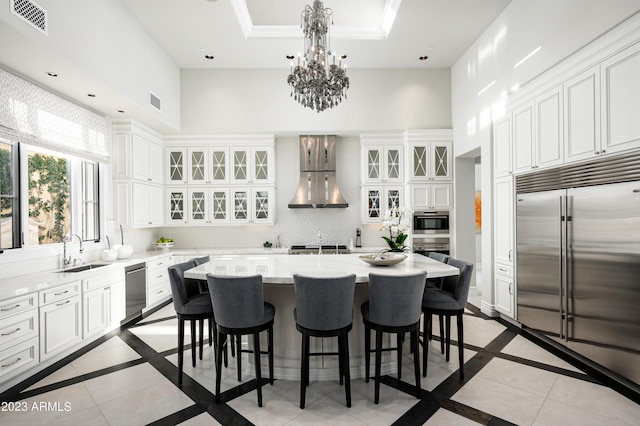 kitchen featuring white cabinetry, sink, a center island, stainless steel appliances, and wall chimney exhaust hood