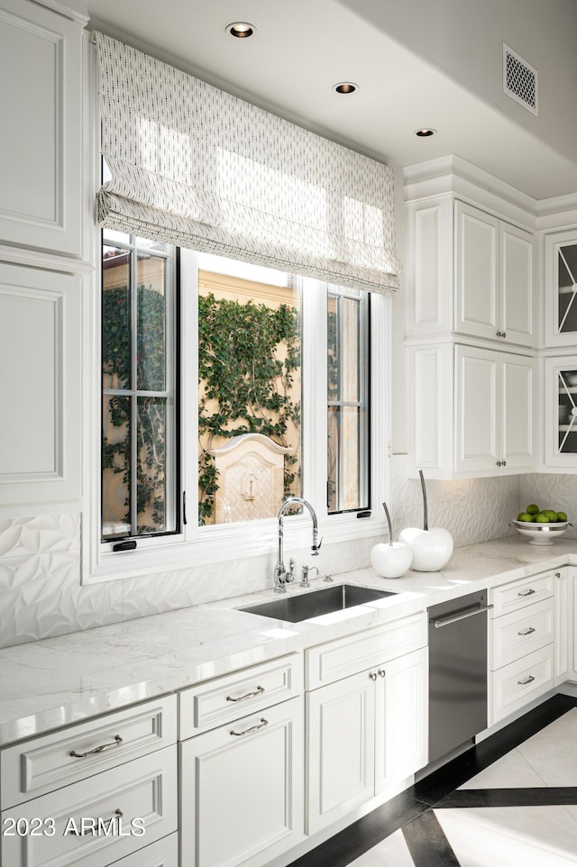 kitchen featuring sink, backsplash, light stone countertops, white cabinets, and stainless steel dishwasher