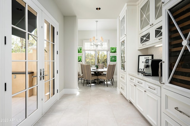 kitchen with light stone counters, pendant lighting, french doors, and white cabinets