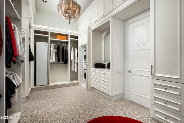 spacious closet featuring stacked washer and clothes dryer, a chandelier, and carpet floors